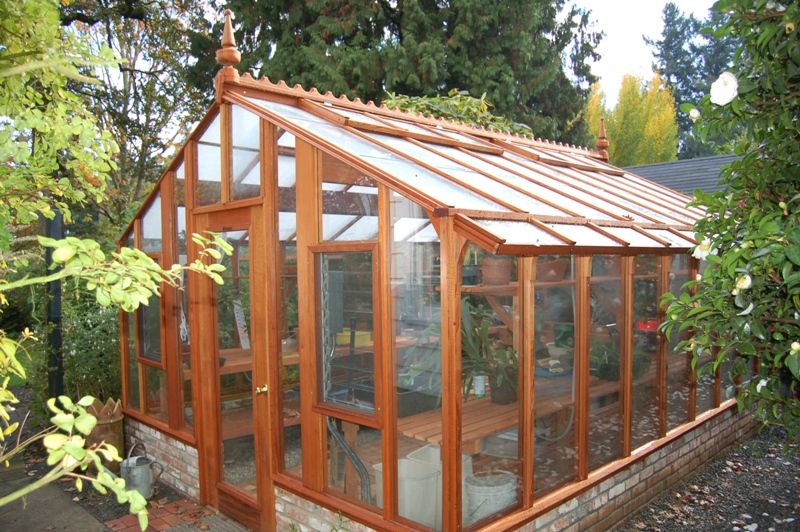 Tall redwood and glass greenhouse with Jalousie windows