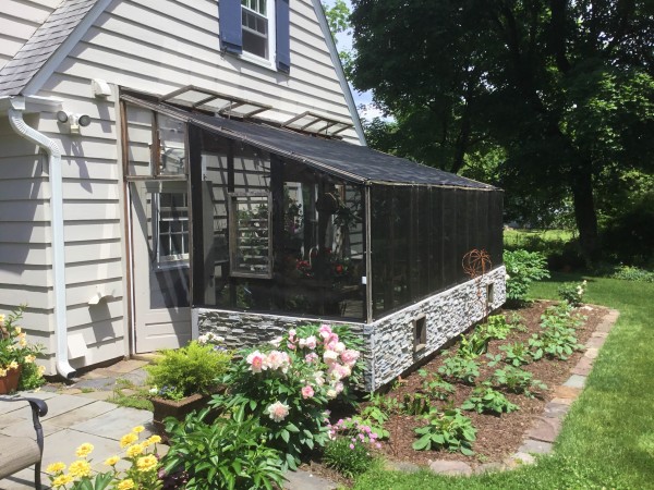 Exterior of 10x18 Lean-to greenhouse with  two 2x8 redwood beams used as a patio space