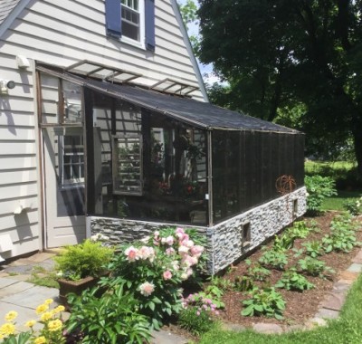 Exterior of 10x18 Lean-to greenhouse with  two 2x8 redwood beams used as a patio space