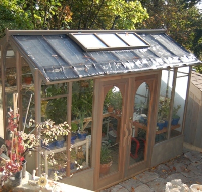 Tall wood greenhouse on a small patio