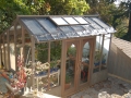 Tall wood greenhouse on a small patio