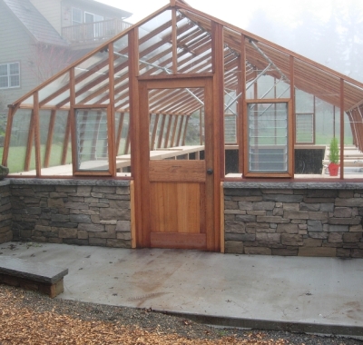 Large home greenhouse on stone base wall
