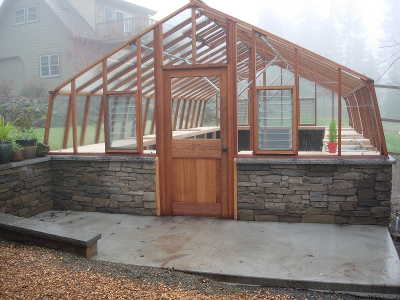 Large home greenhouse on stone base wall