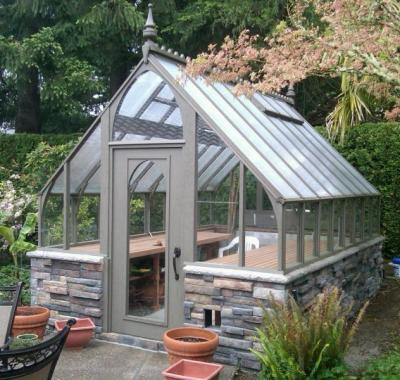 Redwood greenhouse stained gray with stone base