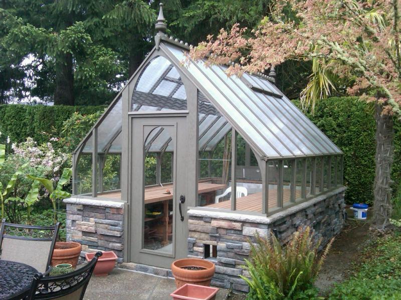 Redwood greenhouse stained gray with stone base