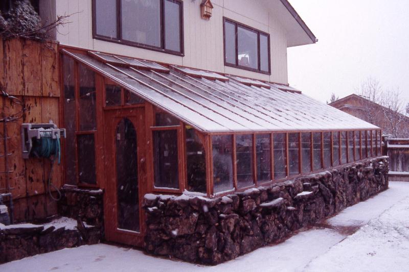 Redwood lean-to greenhouse with stone base